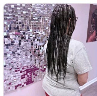 Knotless braids styled in front of the Signature Wall